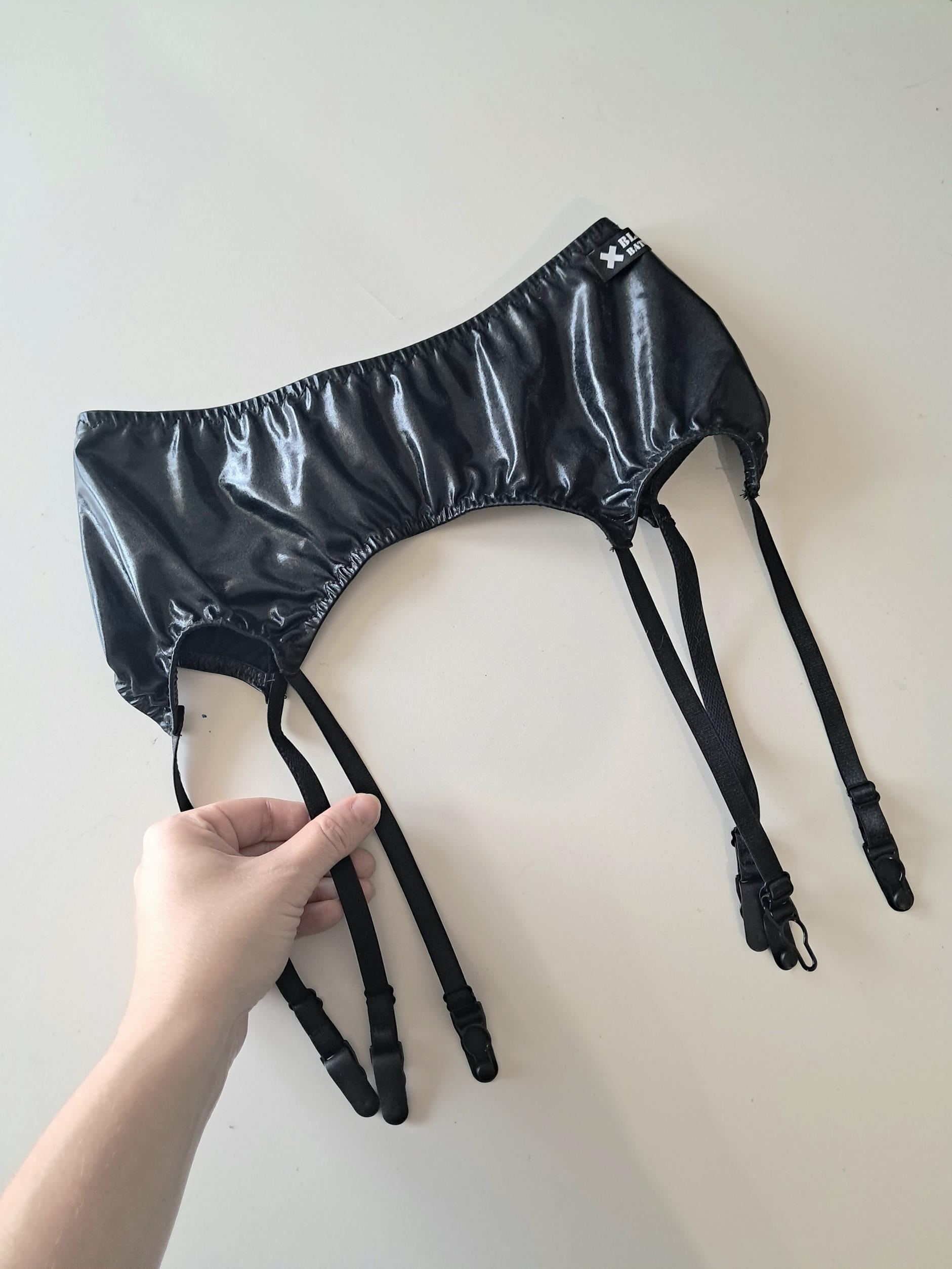 Black wet look garter belt with straps on a white background