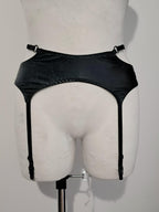 Black wet look strappy garter belt on a mannequin against a plain background